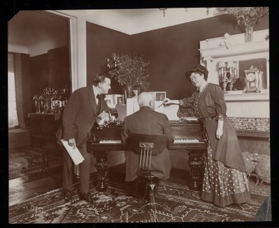 Clara De Regand wijst naar een partituur terwijl een man piano speelt, 1910 door Byron Company